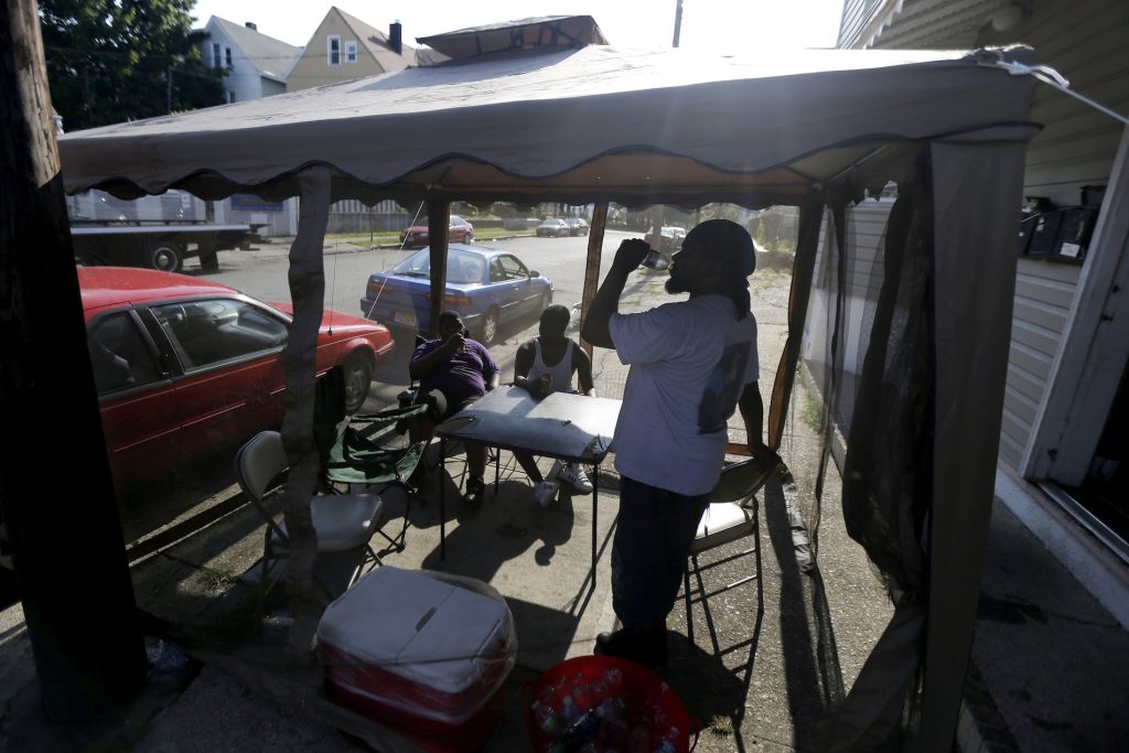 Dave Bailey, Daquan Bailey, Davandre Bailey FILE - In this Wednesday, July 4, 2012 file photo, Dave Bailey, right, gulps water from a bottle while hanging inside of a tent on the sidewalk with his sons Daquan Bailey, 14, left, and Davandre Bailey, 17, while beating the heat on Fourth of July in Paterson, N.J. According to a study published Tuesday, May 25, 2021 in Nature Communications, during the summer of 2017 in nearly all large urban areas, people of color are exposed to more extreme urban heat than white people. (AP Photo/Julio Cortez, File)