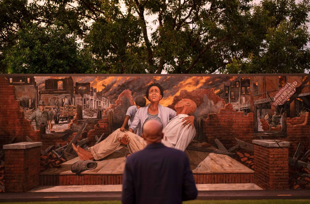 Tulsa Race Massacre History Impact In this Thursday, May 27, 2021 file photo, Darius Kirk looks at a mural depicting the Tulsa Race Massacre in the historic Greenwood neighborhood ahead of centennial commemorations of the massacre in Tulsa, Okla. (AP Photo/John Locher)