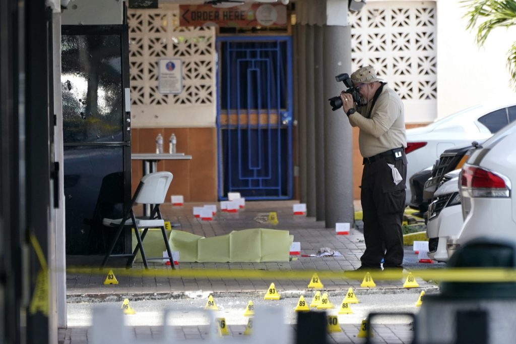 Banquet Hall Shooting Police take photos at the scene of a shooting outside a banquet hall, with evidence markers seen on the ground