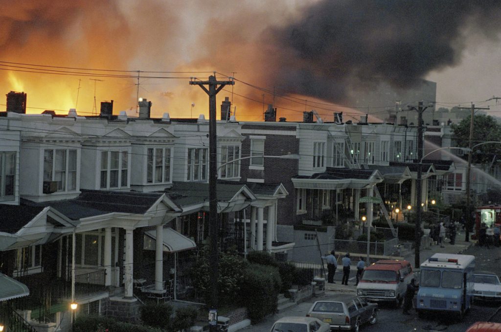 MOVE-Bombing-Remains FILE - In this May, 1985 file photo, scores of row houses burn in a fire in the west Philadelphia neighborhood. Police dropped a bomb on the militant group MOVE's home on May 13, 1985 in an attempt to arrest members, leading to the burning of scores of homes in the neighborhood. A day after Philadelphia's health commissioner was forced to resign over the cremation of partial remains thought to belong to victims of a 1985 bombing of the headquarters of a Black organization, the city now says those victims' remains were never destroyed. City officials told the victims' family Friday, May 14, 2021 that a subordinate had disobeyed Health Commissioner Thomas Farley’s 2017 order to dispose of the remains. (AP Photo/File)