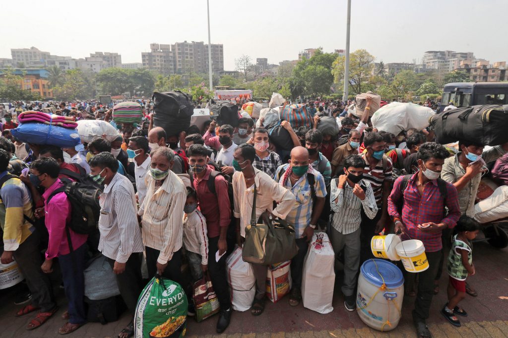 People line up to board trains in Mumbai, India, last month. Migrant workers were swarming rail stations in the country's financial capital to go to their home villages as virus-control measures dried up work in the hard-hit region. (Rafiq Maqbool/AP Photo)