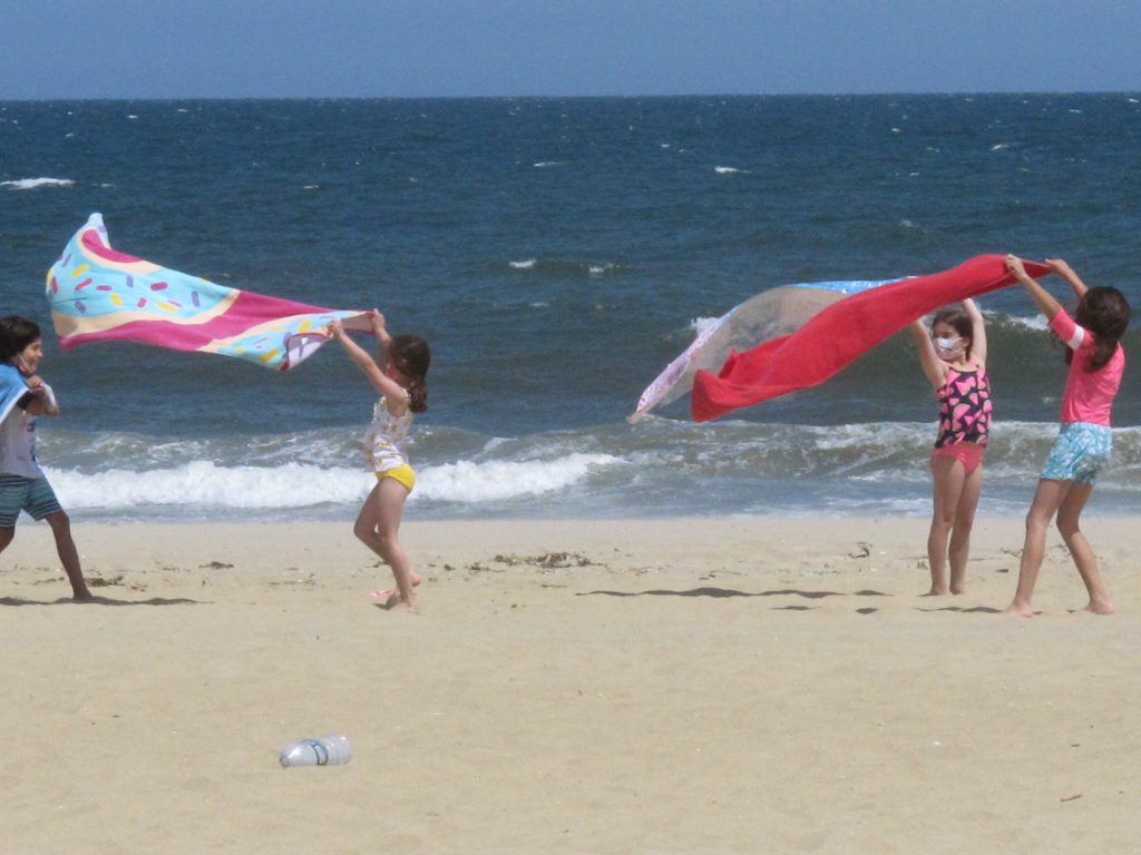 Children play with beach towels on a windy day in Belmar, N.J., on Tuesday. Millions are expected to hit the road or board a plane to celebrate Memorial Day weekend as more people get vaccinated and COVID-19 restrictions are scaled back. Children play with beach towels on a windy day in Belmar, N.J., on Tuesday. Millions are expected to hit the road or board a plane to celebrate Memorial Day weekend as more people get vaccinated and COVID-19 restrictions are scaled back. (Wayne Parry/AP Photo)