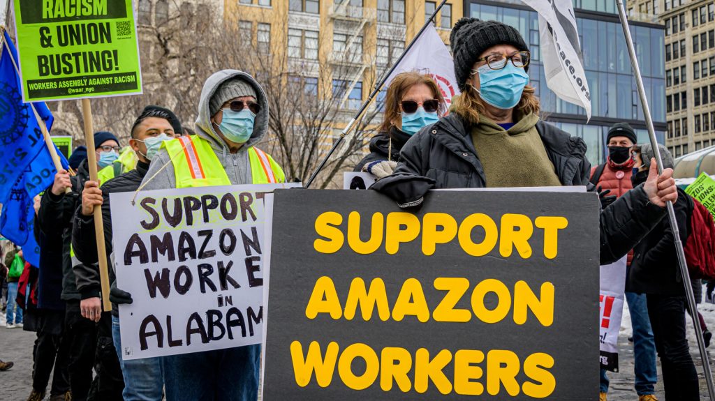 Participants seen holding signs and marching on a picket Protesters hold signs that read