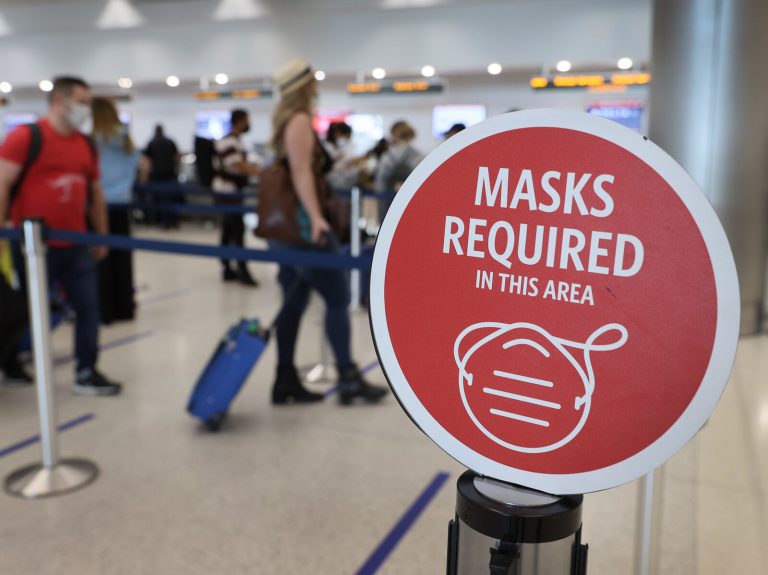 People wait in line at an airport, with a 