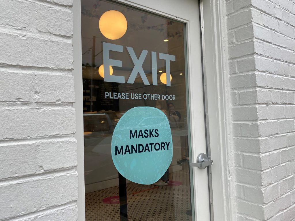 Some businesses, including Jeni’s Splendid Ice Creams, are still requiring customers to wear masks indoors, despite new guidance from the CDC that it’s safe for fully vaccinated people to go without them. A sign says