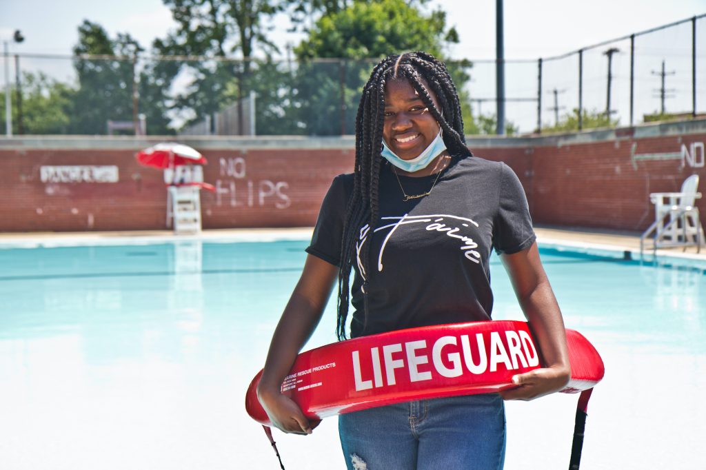 phillypools-lifeguards-06 Faith Bradley stands with lifeguard equipment in front of a pool