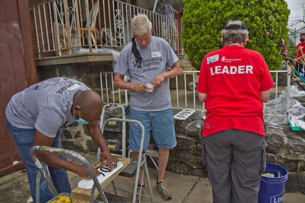 2021-06-04-k-paynter-rebuilding-together-6000-callowhill Volunteers with Rebuilding Together Philadelphia create address signs for homes on the 6000 block of Callowhill Street in the city’s Haddington neighborhood on June 4, 2021. (Kimberly Paynter/WHYY)