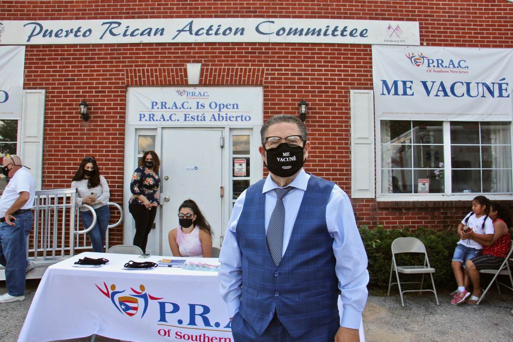 Ralph Padilla stands in front of a vaccine clinic while wearing a black face mask