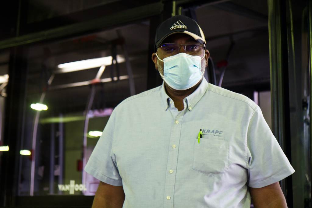 A closeup of Jeffery Gallman wearing a face mask in front of a KRAPF bus