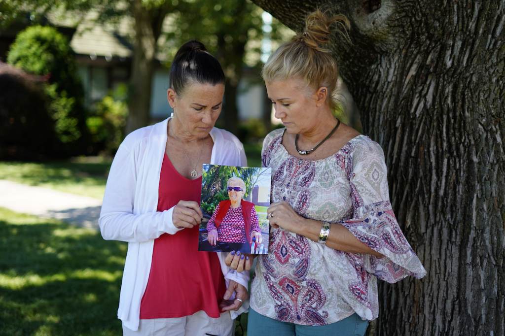 Virus Outbreak Angela Ermold, right, and her sister, Denise Gracely, hold a photo of their mother, Marian Rauenzahn, Thursday, June 17, 2021, in Fleetwood, Pa. Pandemic restrictions are falling away almost everywhere — except inside many of America’s nursing homes. “They have protected them to death,” said Gracely. (AP Photo/Matt Slocum)