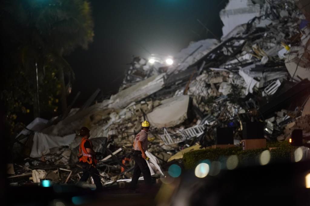 Building Collapse Miami Rescue workers walk beside the rubble as rescue efforts continue