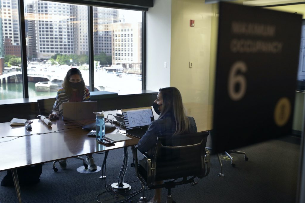 Virus Outbreak Stephanie Jones, left, and Tara Martin, right, work in a conference room while wearing face masks