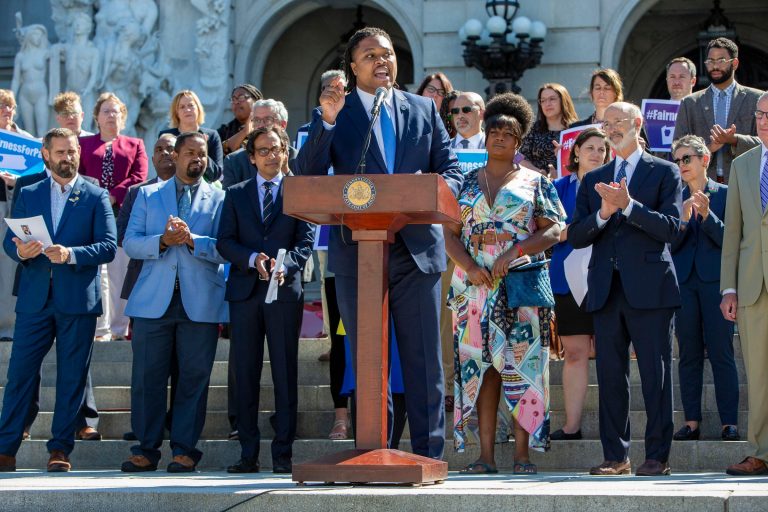 Rep. Malcolm Kenyatta speaks at a podium, with a group of lawmakers behind him