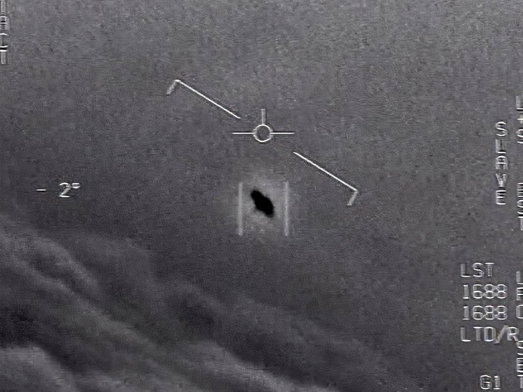 In an image from video footage from 2015, an unexplained object is seen at center as it soars among the clouds, traveling against the wind. “There’s a whole fleet of them,” a naval aviator tells another, though only one indistinct object is shown. In an image from video footage from 2015, an unexplained object is seen at center as it soars among the clouds, traveling against the wind.