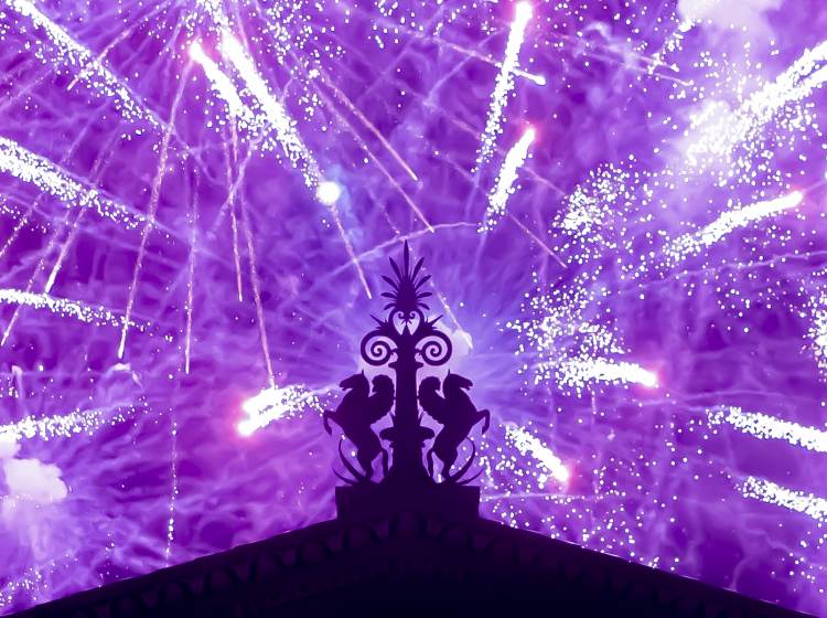 Fireworks explode in the background behind a gargoyle atop of the central portico of the Philadelphia Museum of Art.