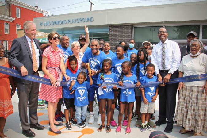 Dana Clark (center), surrounded by children, cuts the ribbon for the reopening of the rebuilt 8th and Diamond Playground,