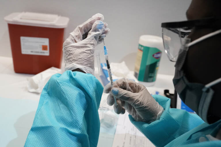A health care worker fills a syringe with the Pfizer COVID-19 vaccine