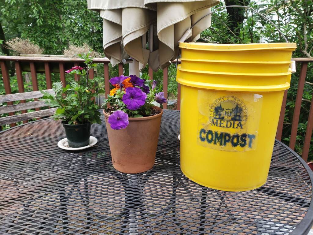 A flower pot sits next to a Media compost bucket.