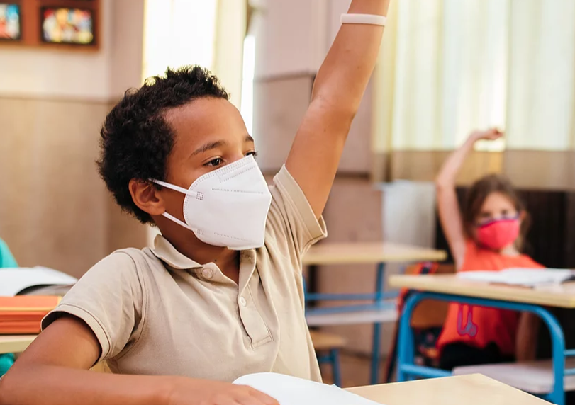 Screenshot 2021-07-23 134735 A masked student raises his hand in class.