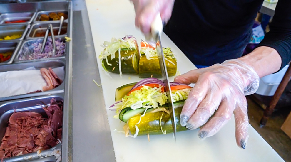 A chef cutting a pickle sandwich at Elsie's Pickles