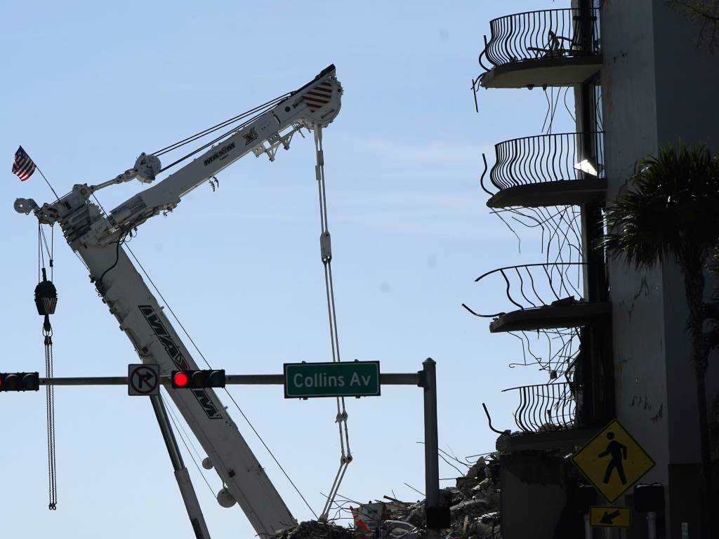 An American flag flies from a crane on July 4th next to the Champlain Towers South condo building, where scores of victims remain missing more than a week after it partially collapsed. An American flag flies from a crane on July 4th next to the Champlain Towers South condo building