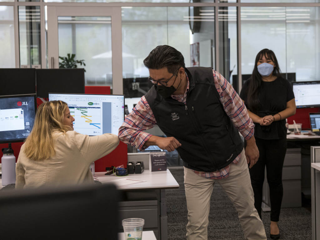 Employees elbow bump at a JLL office in Menlo Park, Calif., last September. With the delta variant surging, mask mandates are returning and some employers are now requiring employees to be vaccinated before coming to the office. Employees elbow bump at a JLL office in Menlo Park, Calif., last September. With the delta variant surging, mask mandates are returning and some employers are now requiring employees to be vaccinated before coming to the office. (David Paul Morris/Bloomberg via Getty Images)