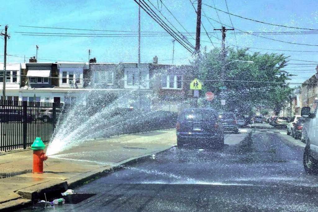 hydrant-sprinkler A fire hydrant is open on a city street