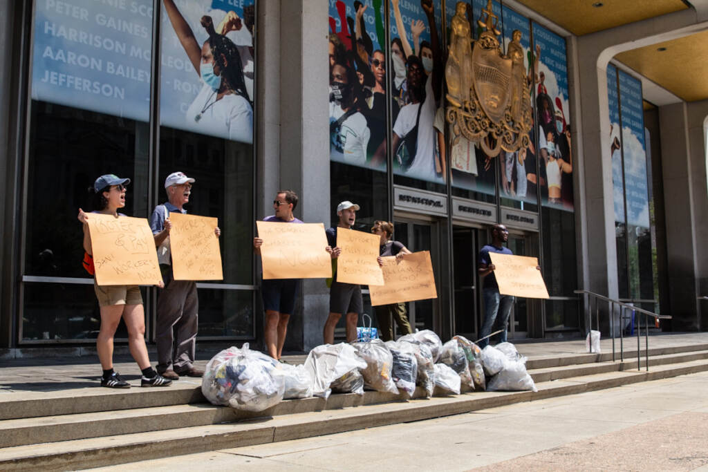 trashman-protest-msb2 Protesters hold signs in front of bags of trash on the steps of the MSB