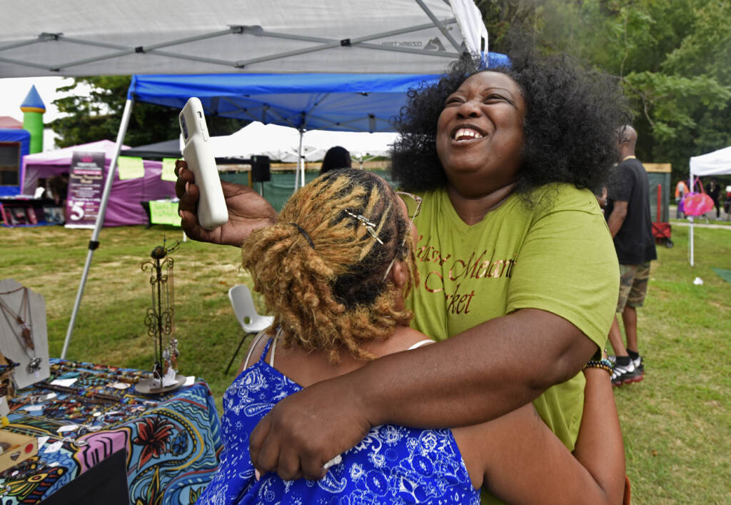 Two people embrace at grand opening of the Mask Melanin Market at its new Glassboro, NJ