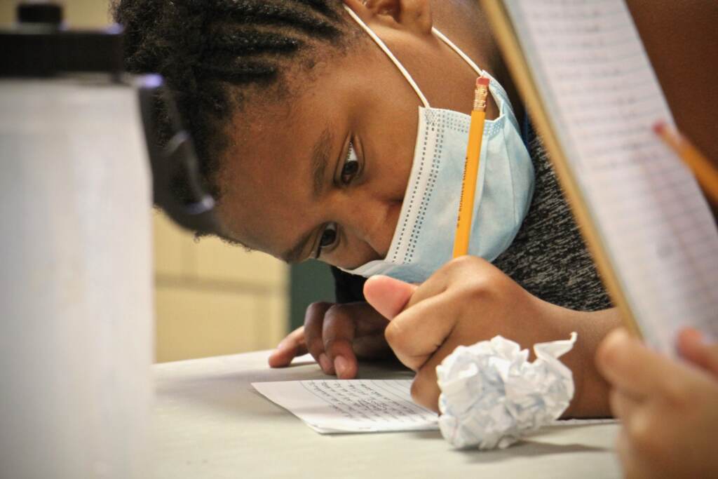 Jaydalee Rivera writes a story while wearing a face mask