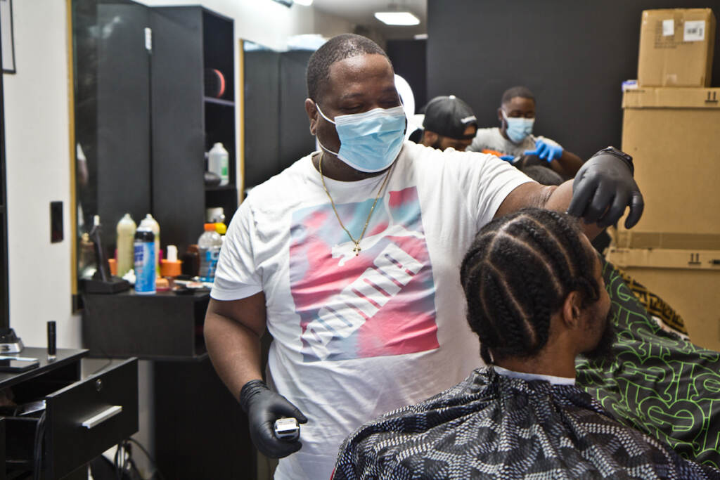Javan Rankines gives someone a haircut while wearing a face mask