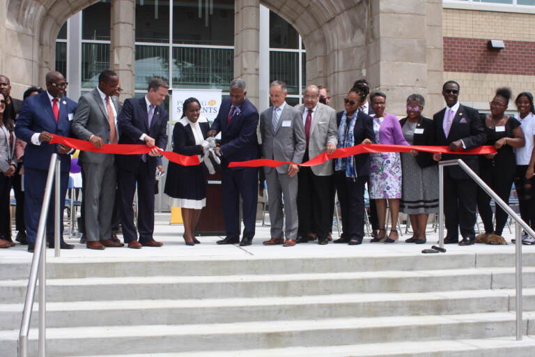 State School District Superintendent Katrina McCombs and Camden Mayor Vic Carstarphen hold the scissors to cut the ribbon on the new Camden High School. Both McCombs and Carstarphen are alumni of the school. (P. Kenneth Burns/WHYY)