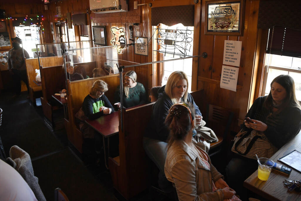 Virus Outbreak Connecticut Diners eat and drink at the Hungry Rhino restaurant in Windsor Locks, Conn., Friday, March 19, 2021. Beginning today, limits have been lifted at Connecticut restaurants, non-theater indoor recreation centers, libraries, museums, aquariums, gyms and fitness centers, retail shops, offices, personal services establishments and houses of worship. Mask-wearing, distancing and cleaning protocols will still be required. (AP Photo/Jessica Hill)