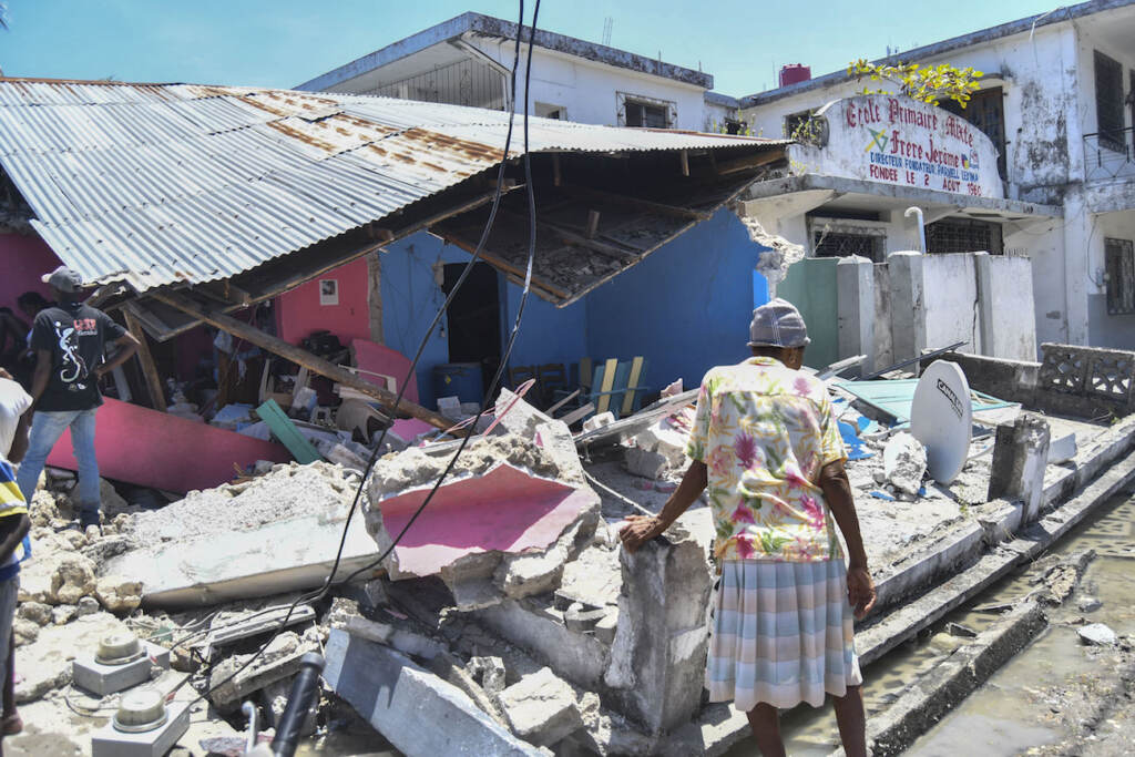 Haiti Earthquake A woman stands in front of a destroyed home in the aftermath of an earthquake in Les Cayes, Haiti, Saturday, Aug. 14, 2021. A 7.2 magnitude earthquake struck Haiti on Saturday, with the epicenter about 125 kilometers ( 78 miles) west of the capital of Port-au-Prince, the US Geological Survey said. (AP Photo/Duples Plymouth)