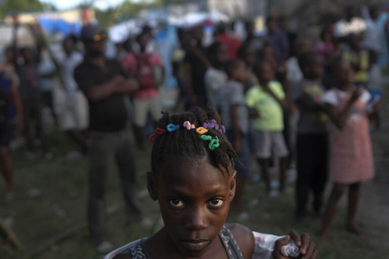 A girl waits with other earthquake victims for the start of a food distribution in Les Cayes, Haiti, Saturday, Aug. 21, 2021, seven days after a 7.2 magnitude earthquake hit the area. (AP Photo/Matias Delacroix)