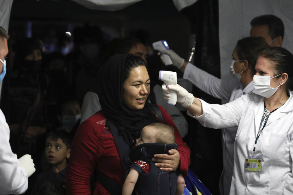 APTOPIX Albania Afghanistan Health workers checks the temperature of evacuated citizens from Afghanistan upon their arrival at Tirana International Airport in Tirana, Albania, Friday, Aug. 27, 2021. A government decision has planned that the Afghans may stay at least a year during which they will proceed with their application for special visas before they move on to the US for final settlement. (AP Photo/Franc Zhurda)