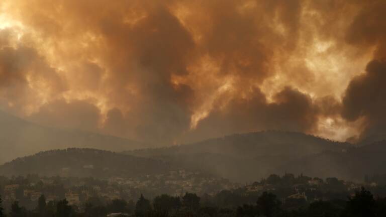 Smoke spreads over Parnitha mountain during a wildfire in the village of Ippokratios Politia