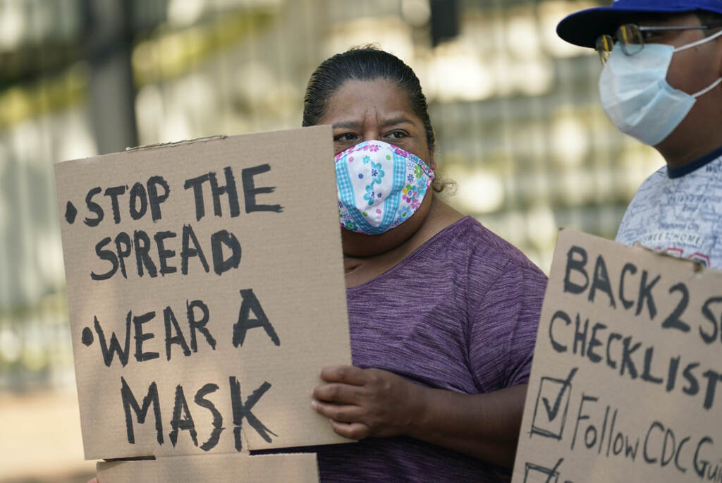 Virus Outbreak-Texas Masks A person holds up a sign that says,
