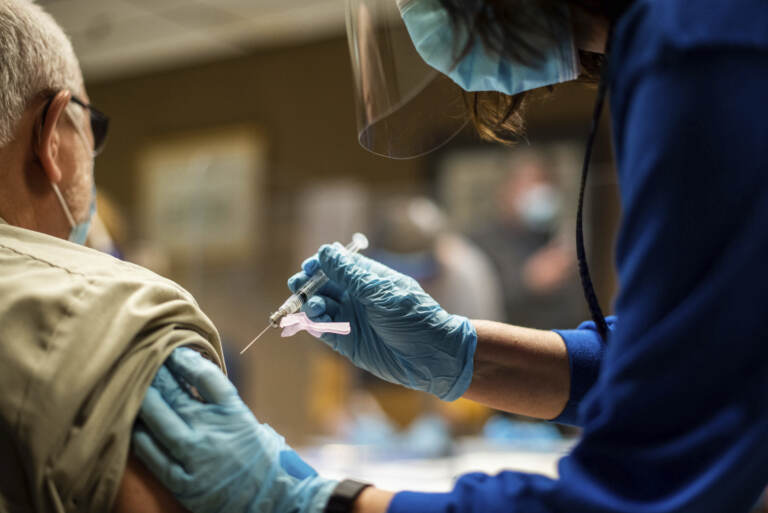 A person receives a COVID-19 vaccination from a health worker