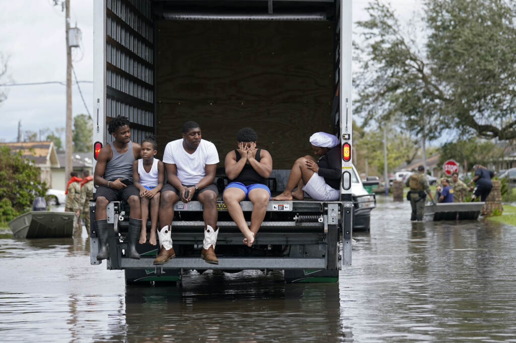 A family sits on the back of a truck amid floodwaters