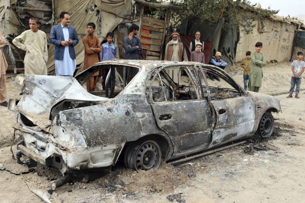 Locals view a vehicle damaged by a rocket attack in Kabul