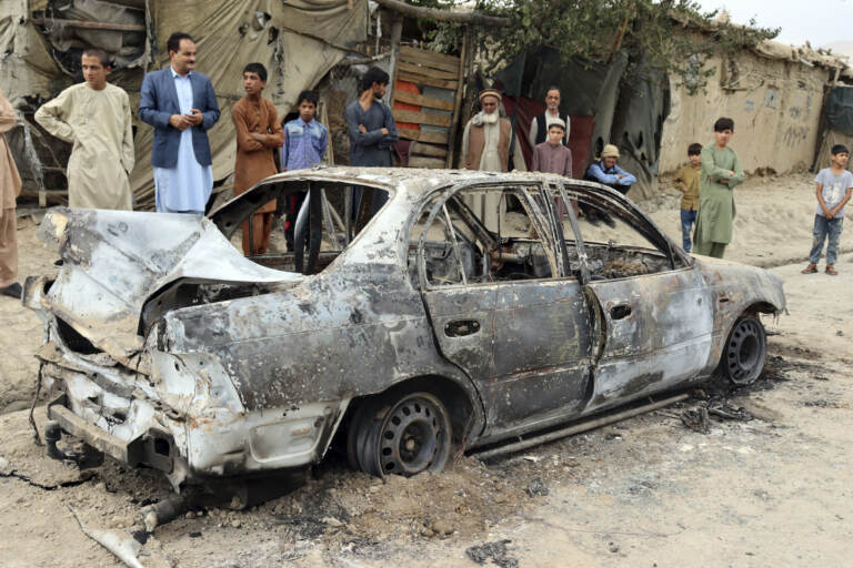 Locals view a vehicle damaged by a rocket attack in Kabul