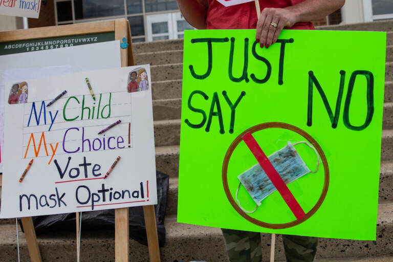 Two parents held signs outside the North Penn school district board meeting against mask mandates in the classrooms