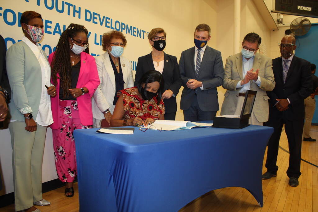 IMG_9088 N.J. Lt. Gov. Sheila Oliver - as acting governor - signs into law a bill that sets asides more than $8 million over two years to pilot a program in four cities that will help youth offenders get reintegrated into the community. (P. Kenneth Burns/WHYY)