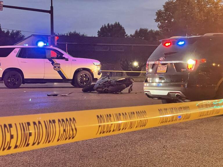 A motorcycle is pictured beside police vehicles and crime scene tape