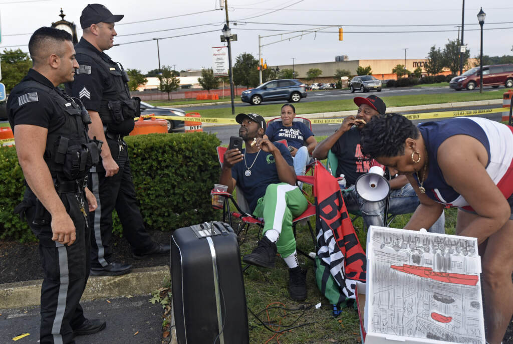 amden activist Gary Frazier (center) and other protesters eat pizza and chat with Deptford police officers