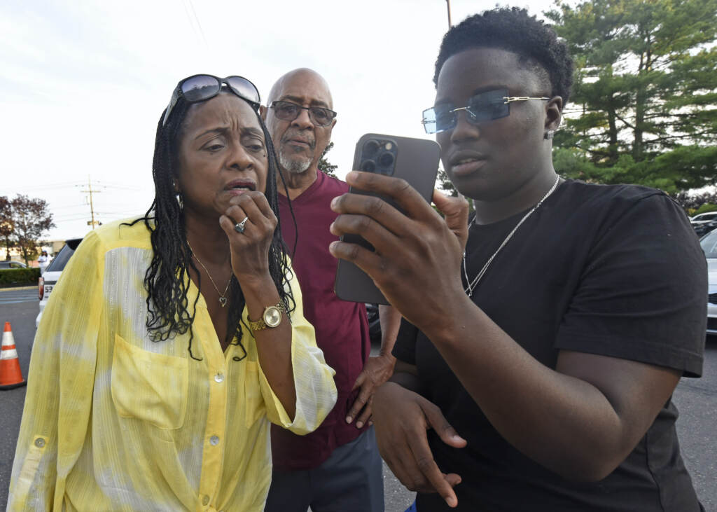 Ajahnae Weal shows arriving customers a video via cell phone