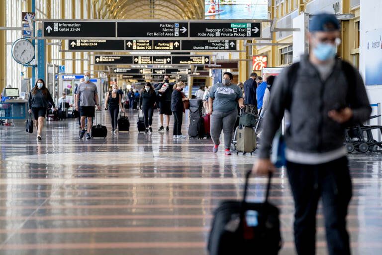 Travelers wearing protective masks walk through Ronald Reagan National Airport in Arlington, Va., in May. (Stefani Reynolds/Bloomberg via Getty Images)