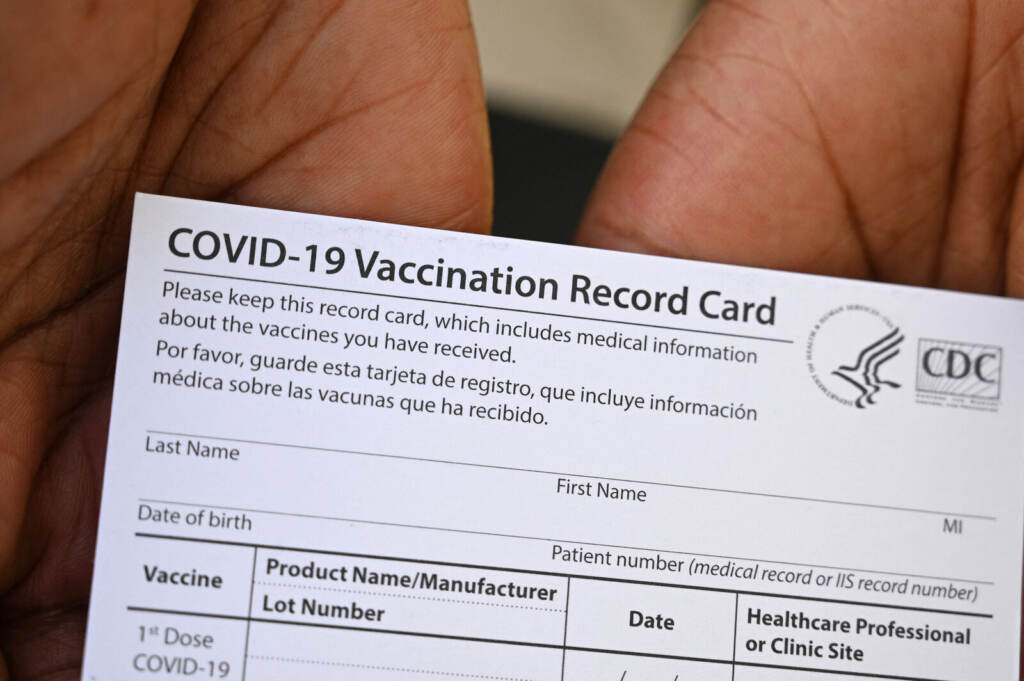 US-HEALTH-VIRUS-EDUCATION-CALIFORNIA A health care worker displays a COVID-19 vaccination record card