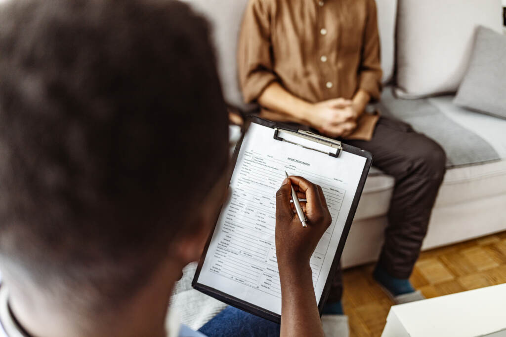 A psychologist is pictured writing notes during a therapy session with a patient